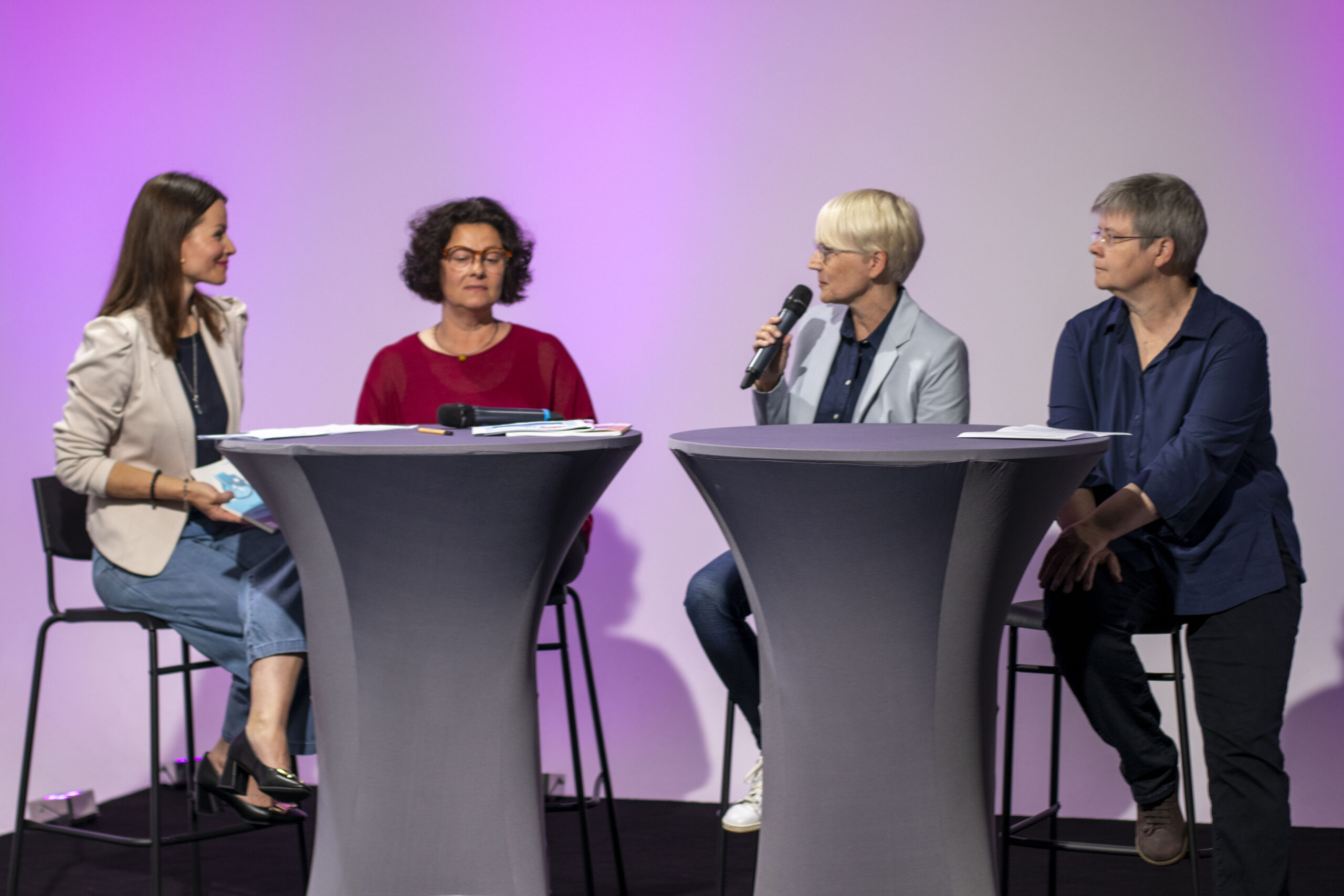 Frau Kubitz, Frau Wagner, Frau Prof. Lauer und Frau Dr. Wagner sitzen auf Barhockern auf der Bühne des Fachtags und diskutieren